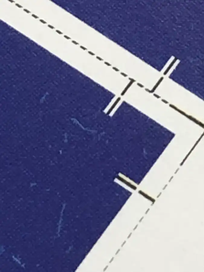 Detalhe de impresso com marcas de corte e linhas de dobra, com o fundo azul avançando além do corte